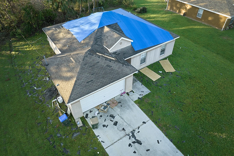 Top view of leaking house roof covered with protective tarp sheets against rain water