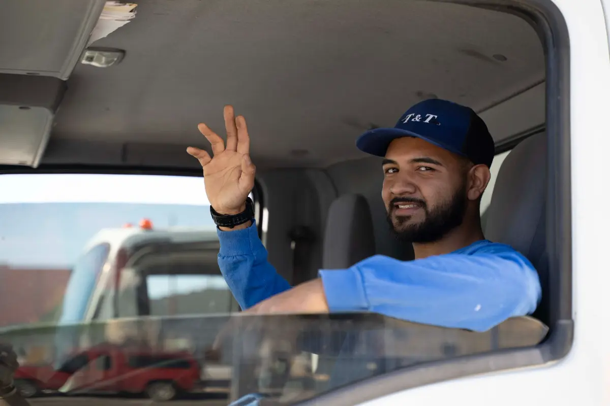 T&T technician waving from the cab of a company truck in Tucson