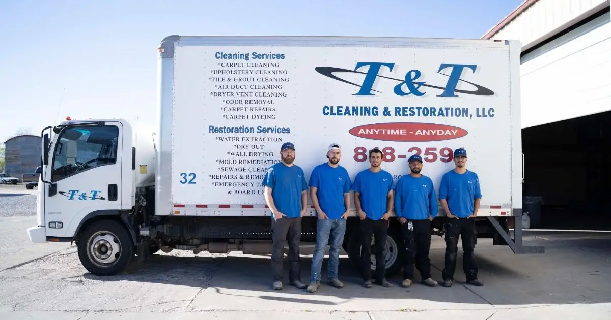 Five T&T Cleaning & Restoration technicians in blue uniforms standing in front of a company box truck in Tucson